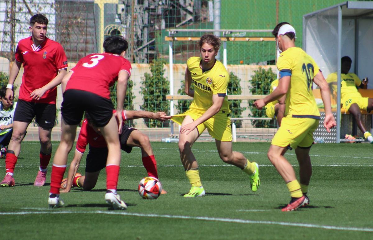 Mario Gil, jugador del juvenil del Villarreal, intenta superar a varios adversarios.