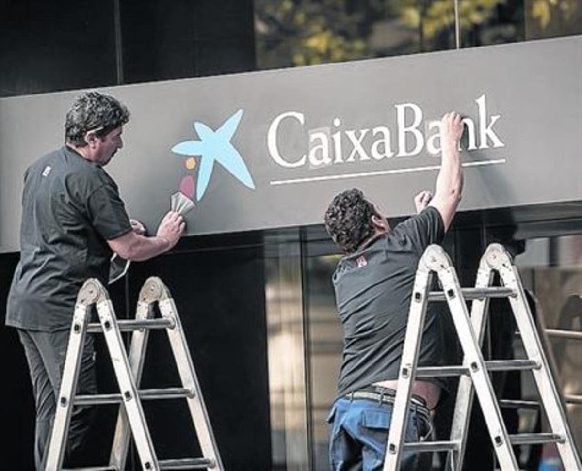 Treballadors canviant ahir els cartells de Barclays.