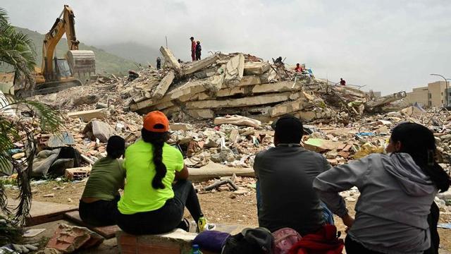 Familiars de víctimes esperen davant de munts de runa per recuperar els cossos dels seus éssers estimats a La Guaira. | MARTÍN BERNETTI / FRANCE PRESSE