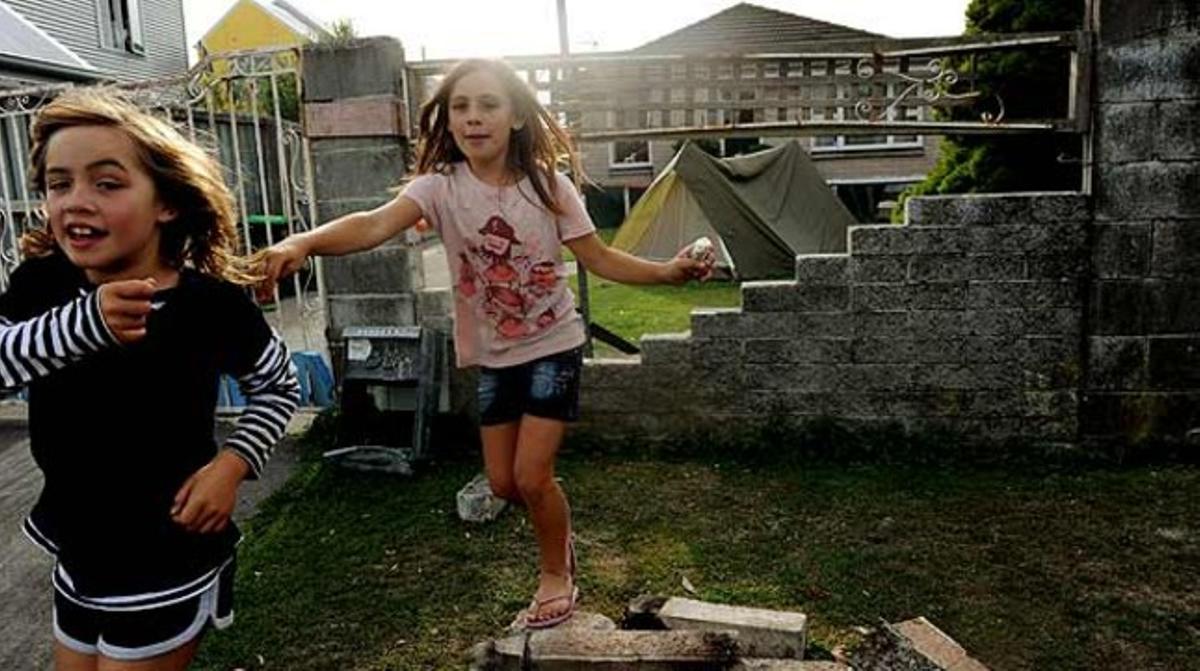 Dues nenes juguen al jardí d’una casa danyada on s’ha muntat una tenda de campanya, a Christchurch (Nova Zelanda). Un terratrèmol de 6,3 graus de magnitud registrat dimarts passat ha matat fins ara 148 persones.