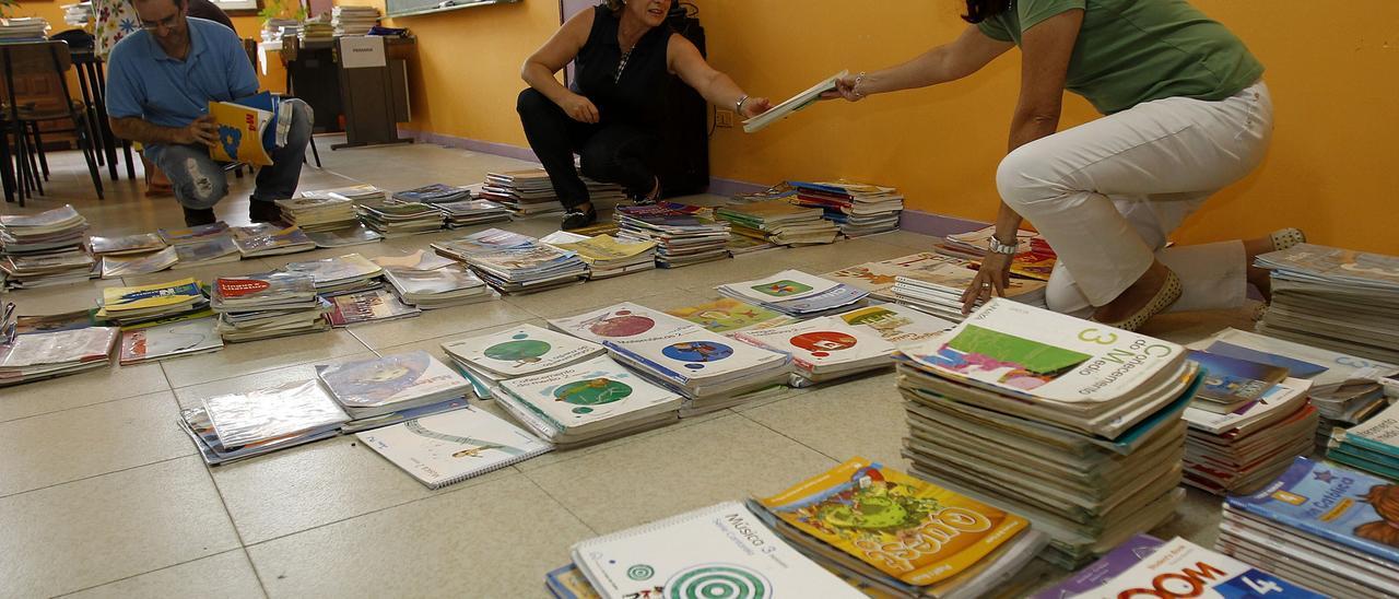 Docentes organizando los libros disponibles en un centro educativo para su reparto.