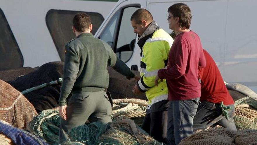 La Guardia Civil acompaña al patrón y el maquinista del pesquero arrestado.