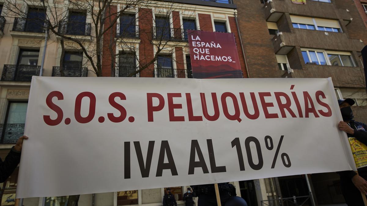 Profesionales del sector de la peluquería y estética muestran una pancarta donde se puede leer &quot;SOS Peluquerías IVA al 10%&quot;.