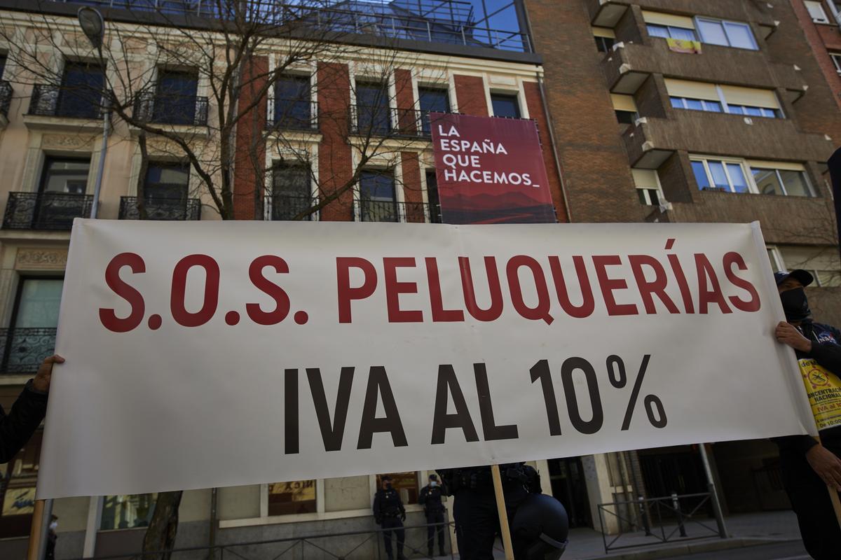 Profesionales del sector de la peluquería y estética muestran una pancarta donde se puede leer &quot;SOS Peluquerías IVA al 10%&quot;.