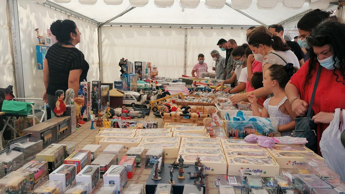 Visitantes de la feria adquieren juguetes antiguos en un punto de venta de la feria