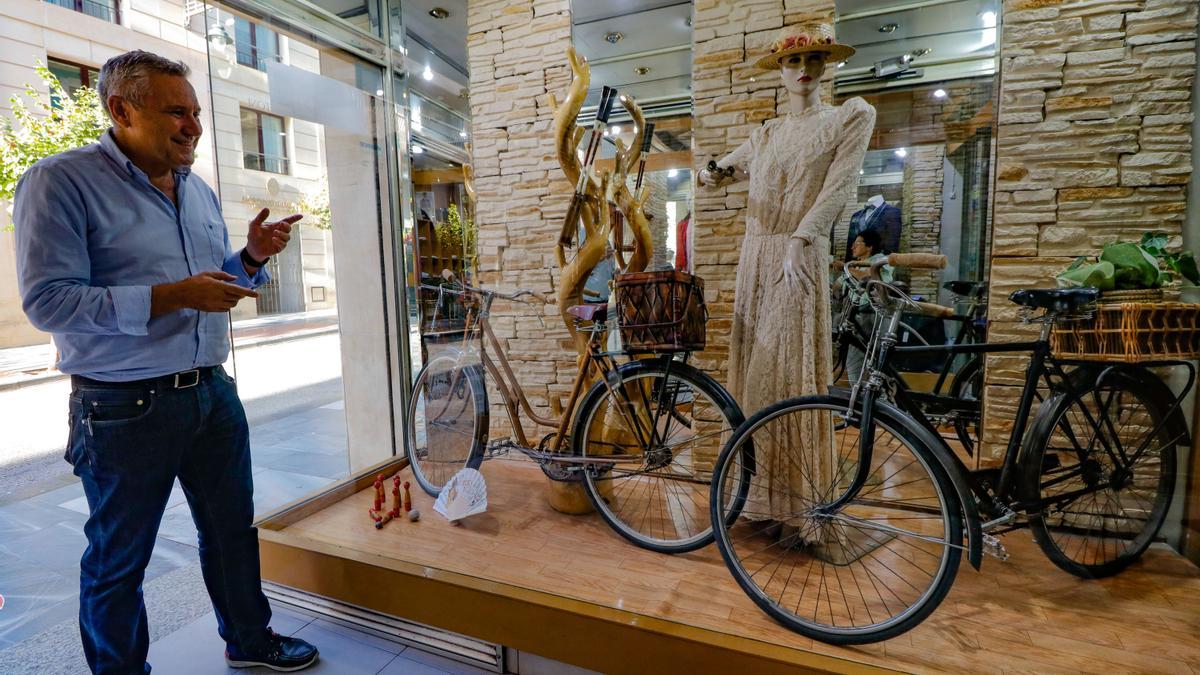Rafael Pérez mostrando las bicicletas y el maniquí caracterizado que ha colocado a la entrada de su tienda.