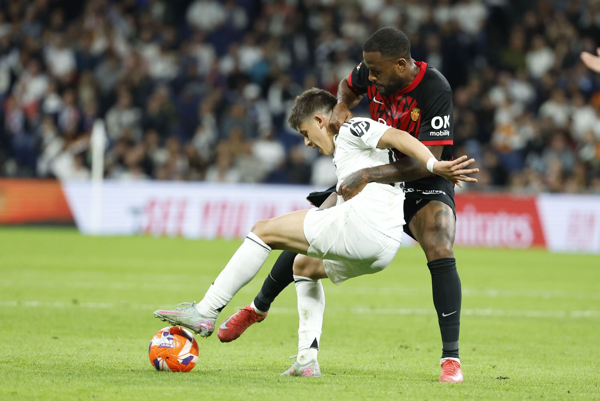 MADRID, 14/05/2025.- El centrocampista turco del Real Madrid Arda Guler (i) lucha con el canadiense Cyle Larin, del Mallorca, durante el partido de la jornada 36 de LaLiga de fútbol que Real Madrid y RCD Mallorca disputan este miércoles en el estadio Santiago Bernabéu. EFE/Chema Moya