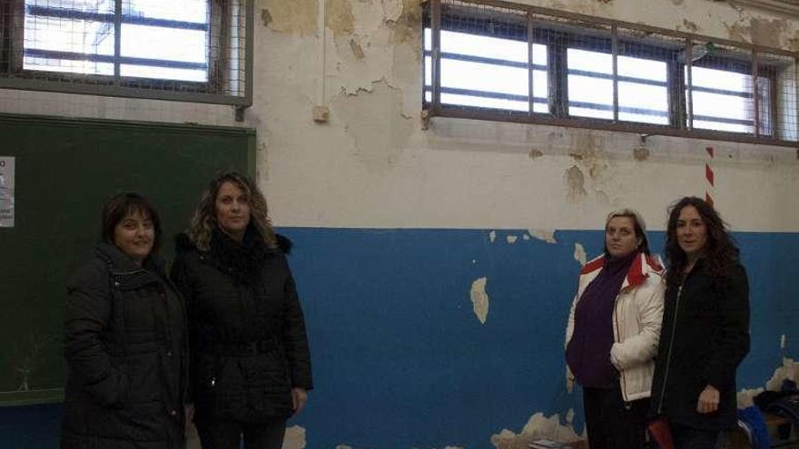 Eva Tamargo, Raquel Menéndez, Eva Vega y Pilar Huerta, en enero, ante las humedades del polideportivo del colegio.