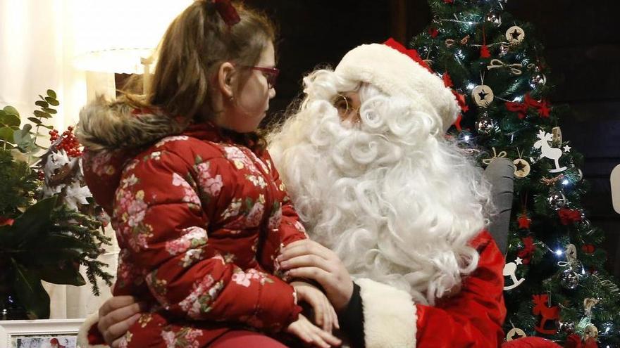 Papá Noel recibiendo a una niña en la casa de madera que le ha habilitado el Concello en Príncipe. // Ricardo Grobas