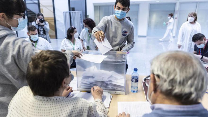 Un trabajador sanitario introduce su voto en una urna emplazada en el atrio del Hospital Universitario Central de Asturias (HUCA). | Irma Collín