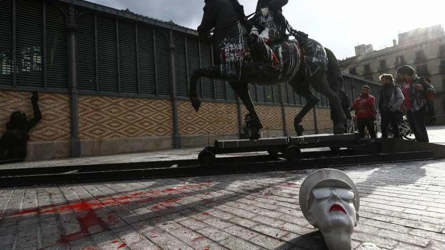 Un busto de Franco, junto a su estatua ecuestre decapitada  |  Un busto de piedra de Franco (en la foto) apareció ayer junto a la estatua ecuestre decapitada del dictador expuesta desde el lunes delante del centro cultural Born de Barcelona, que también amaneció con pintadas y una cabeza de cerdo. Tanto en el cuello del busto como en el de la estatua se hallaron restos de cola. La estatua ecuestre, que forma parte de la exposición &quot;Franco, Victoria, República. Impunidad y espacio urbano&quot;, ha originado una fuerte polémica desde que se anunció la colocación de estatuas franquistas para ilustrarla.