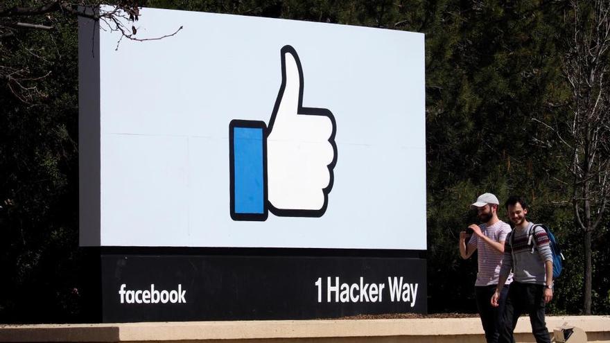 Dos hombres caminan junto a un icono de Facebook.