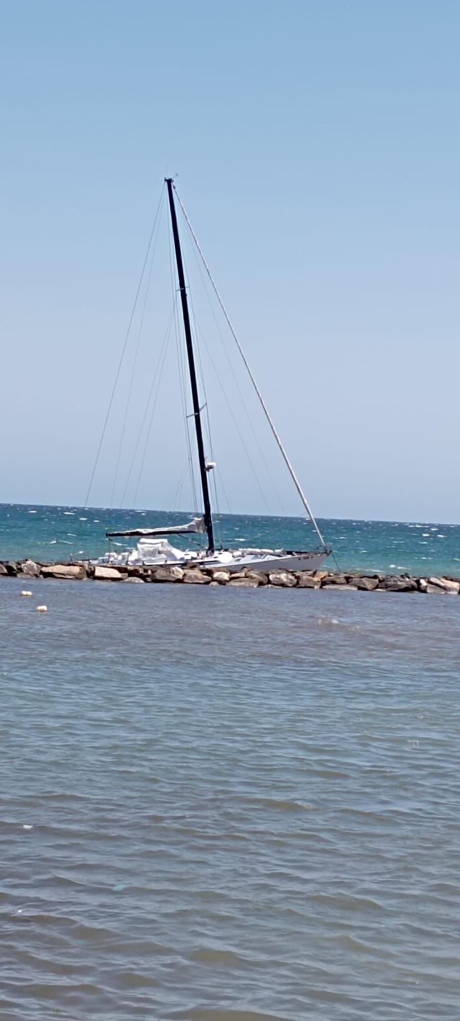 Un velero encalla en las rocas de la escollera de la playa del Cocó