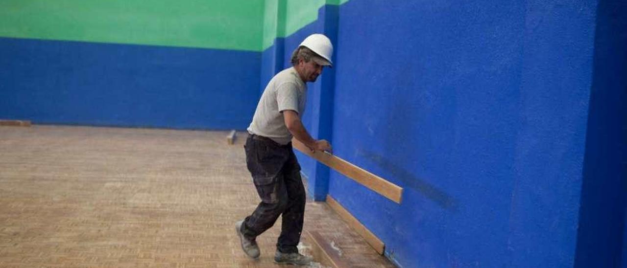 Un operario trabaja en la pista del polideportivo de Riaño.