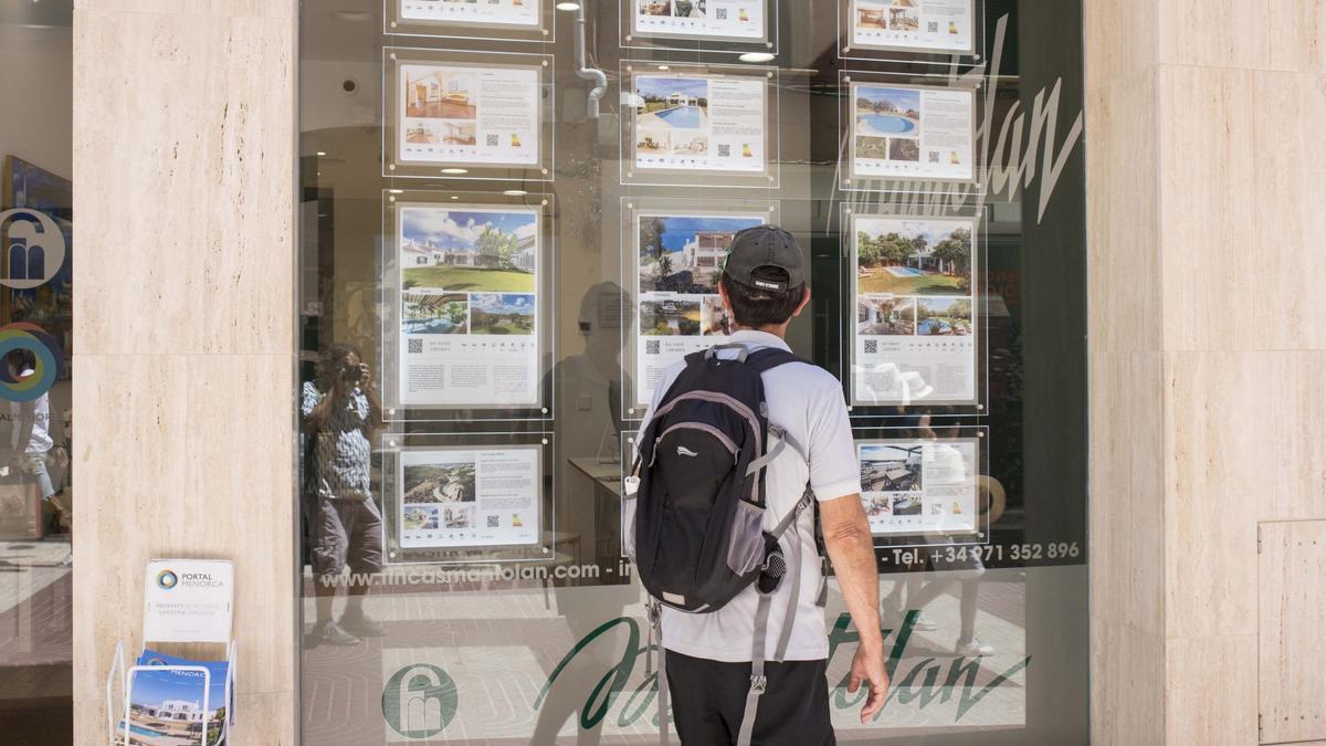 Un hombre ojea el escaparate de una inmobiliaria.