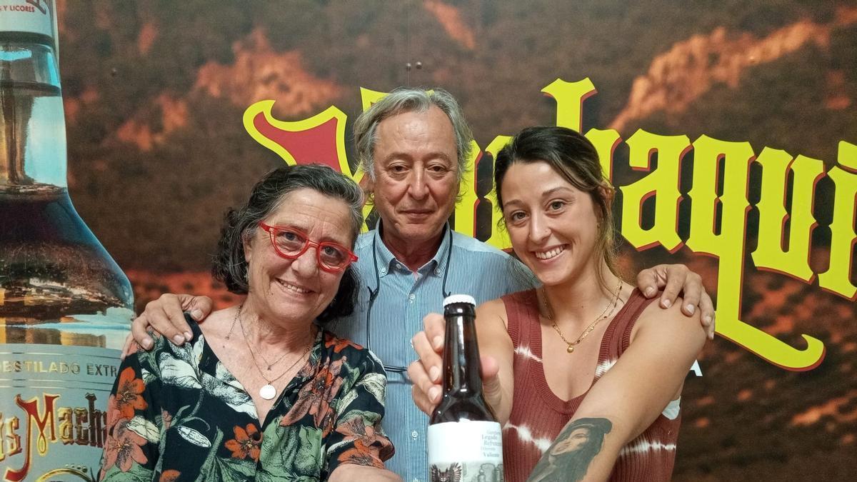 Julia Reyes, gerente de Destilerías Machaquito, posa con sus padres y la nueva cerveza con anís.
