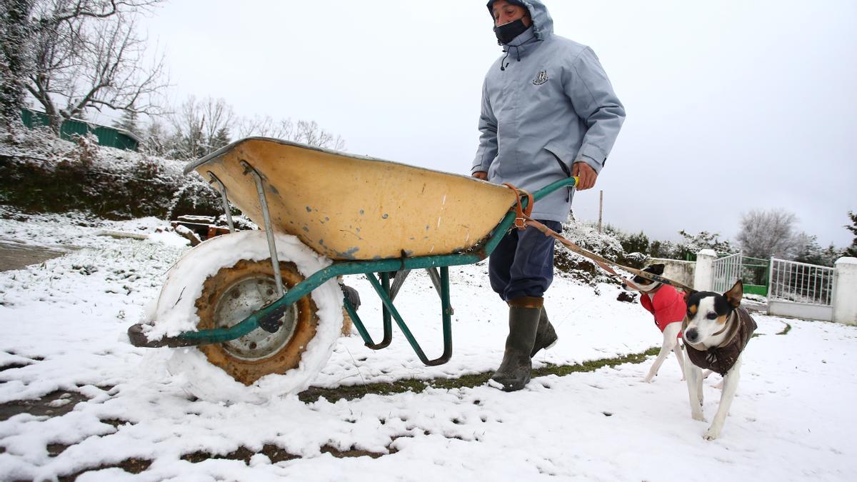 Una hombre lleva una carretilla a pesar de la intensa nevada en la sierra de Béjar, Salamanca.