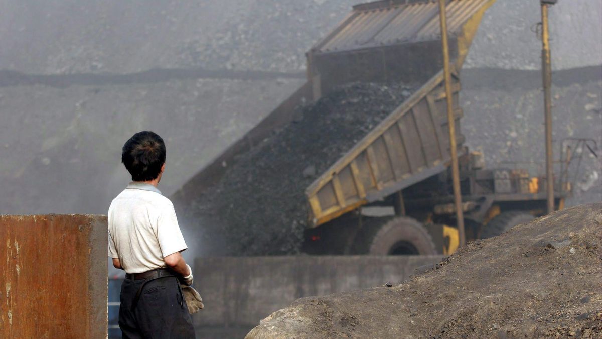 Un trabajador delante de un camion en una mina en China.