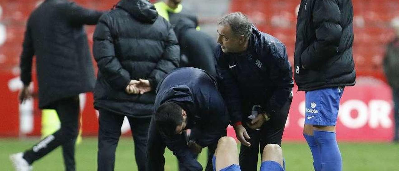 Álvaro Jiménez es atendido por los masajistas del Sporting ante la mirada de Álex Pérez al final de partido.