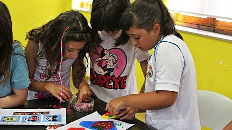 Tres niñas crean en grupo una figura de Hama Beads en el Punto de Información Juvenil.