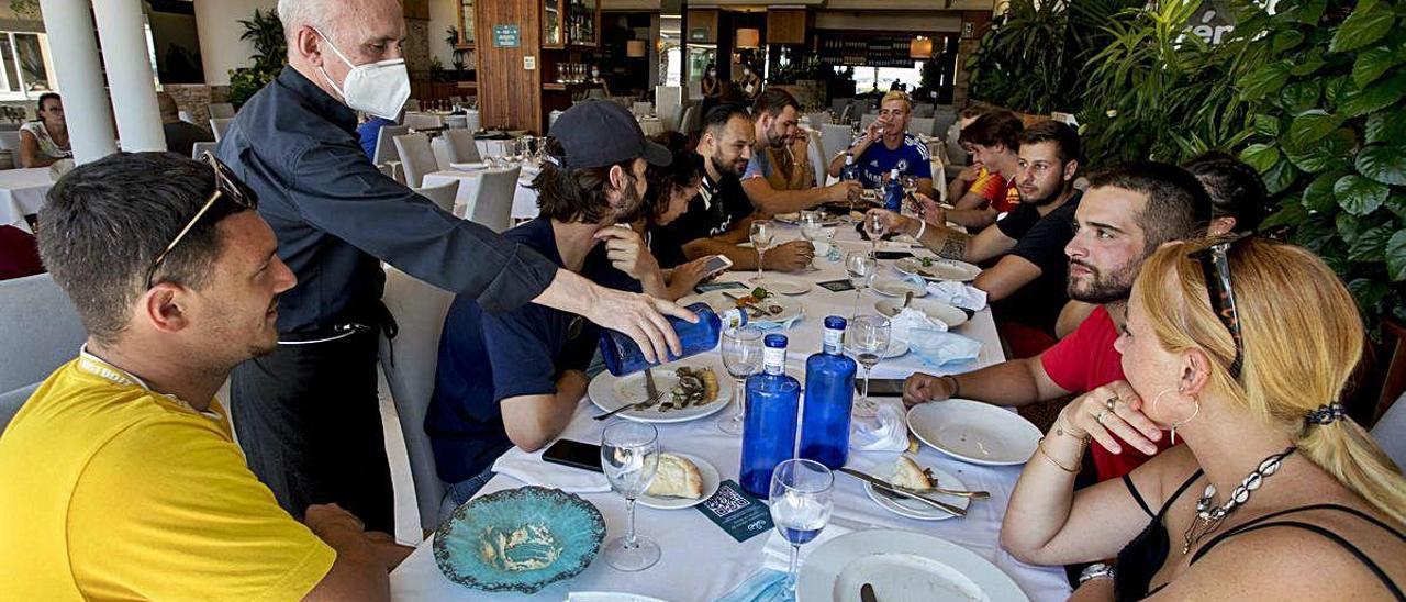 En el restaurante El Coso, en el paseo marítimo, un camarero sirve a una mesa de turistas multitudinaria, no permitida a partir de hoy.