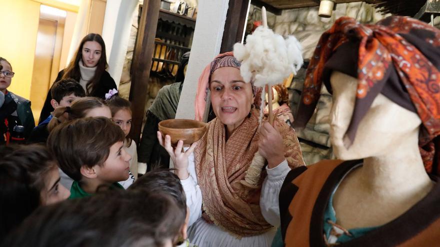 Rosa Cuervo, caracterizada de filandera, al tiempu qu’amuesa una cachada de madera a los escolinos del colexu d’El Quirinal d’Avilés. | Mara Villamuza