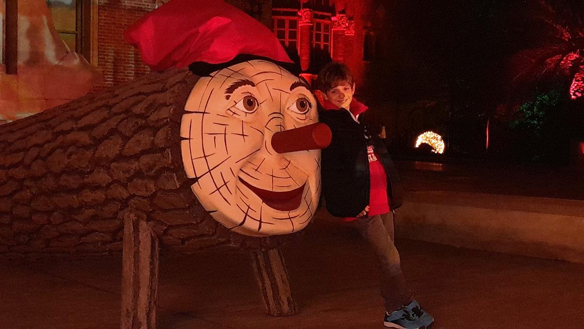 Un niño posa junto al gran Tió navideño.