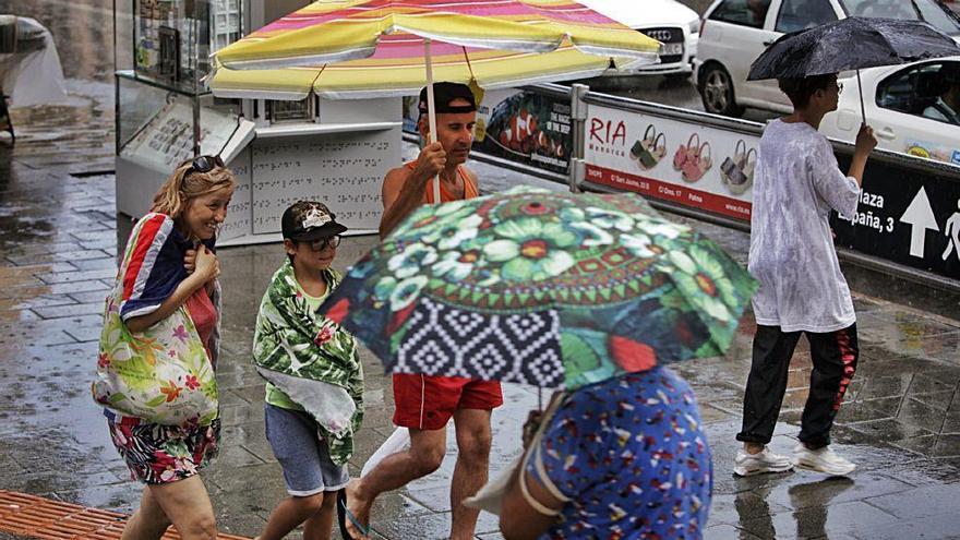 Un grupo de personas se resguarda como puede de la lluvia en Palma.