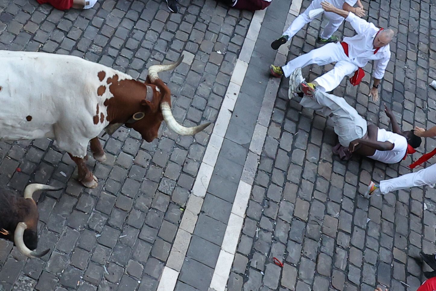 PAMPLONA, 08/07/2025.- Varios corredores caen en el tramo que va desde el final de la cuesta de Santo Domingo a la curva de Mercaderes durante el segundo encierro de los Sanfermines, protagonizado por toros de la ganadería Cebada Gago, este martes, en Pamplona. EFE/ J.P. Urdiroz