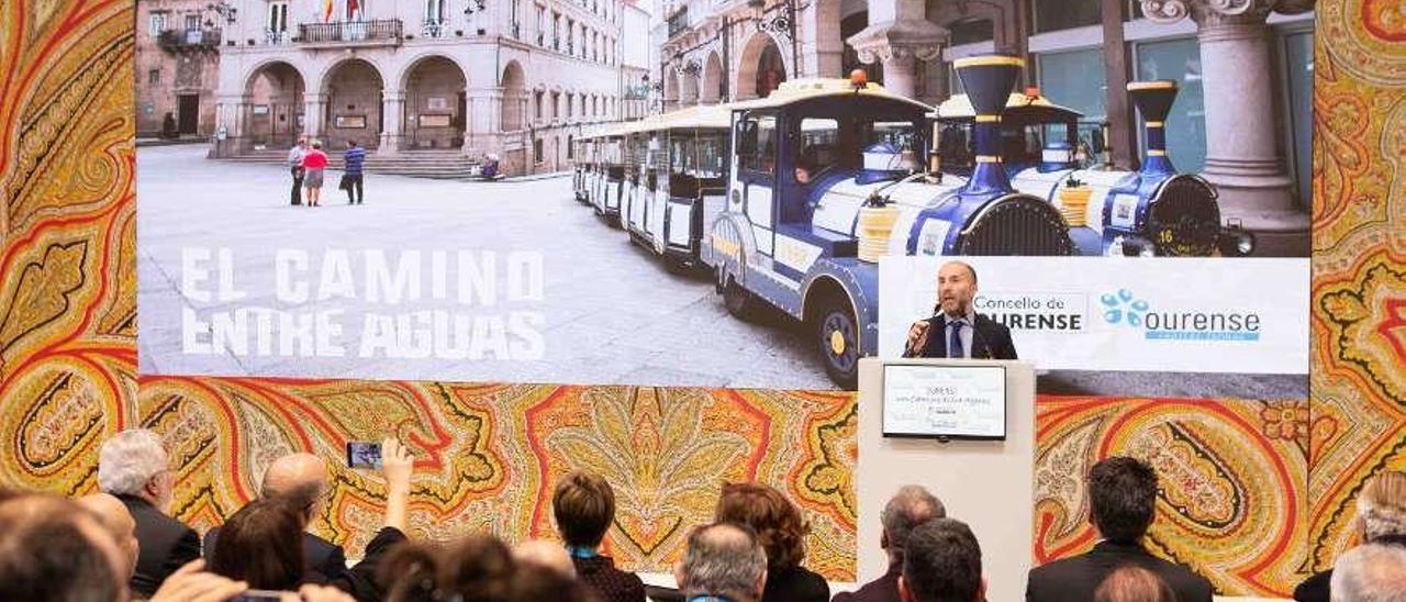 El alcalde durante su ponencia ante el público con una imagen del tren termal. // FdV