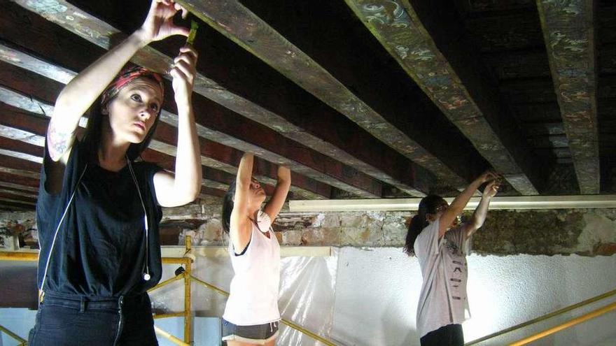 Alumnas eliminan el repinte de las vigas policromadas que conforman el alfarje que será restaurado en la Casa de Cultura.