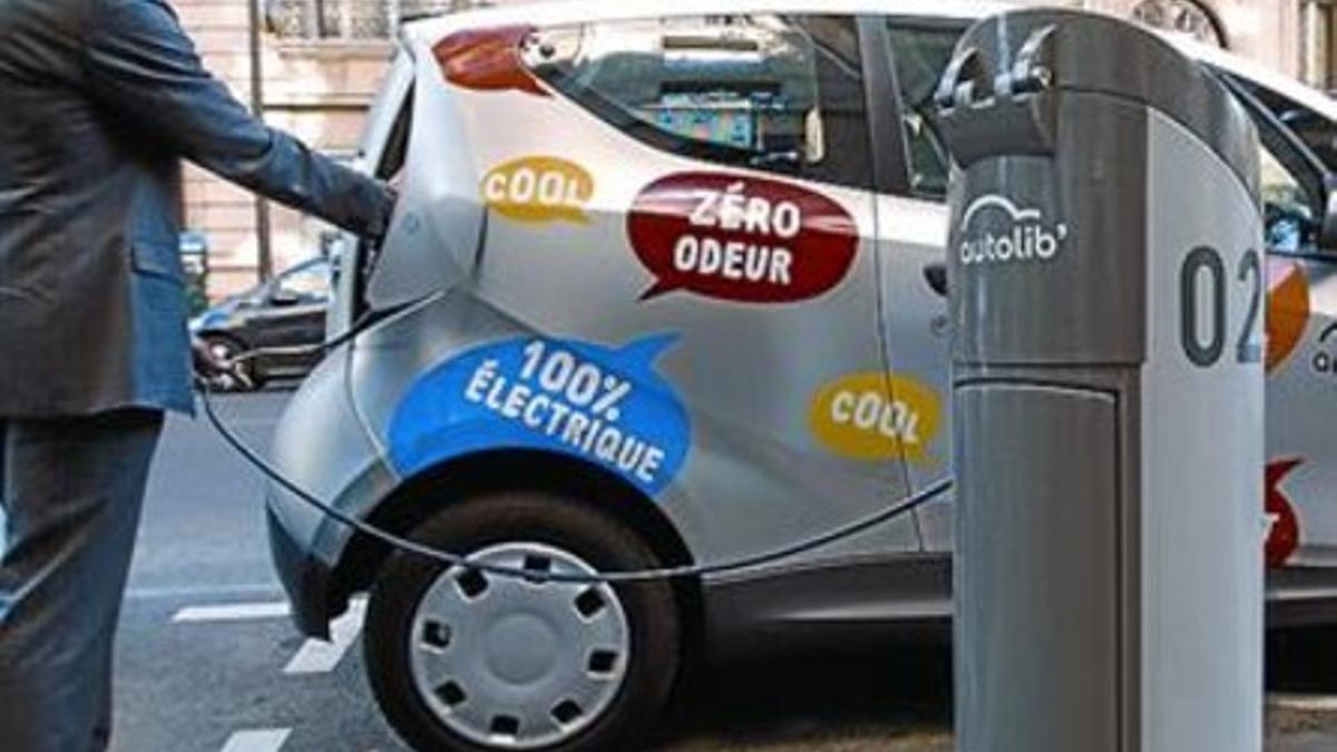 Un responsable del 'autolib' carga la batería de un coche, ayer en París.