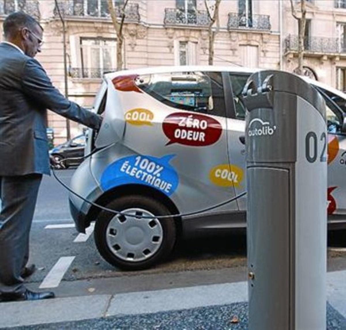 Un responsable del 'autolib' carga la batería de un coche, ayer en París.