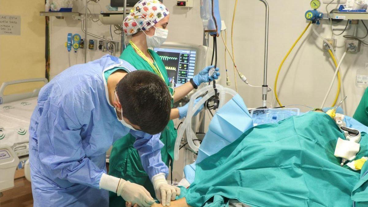 Dos sanitarios atienden a un enfermo en un hospital.