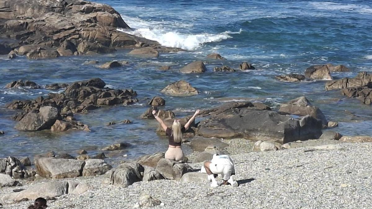 Un joven hace una foto a su acompañante en la playa de Silleiro.