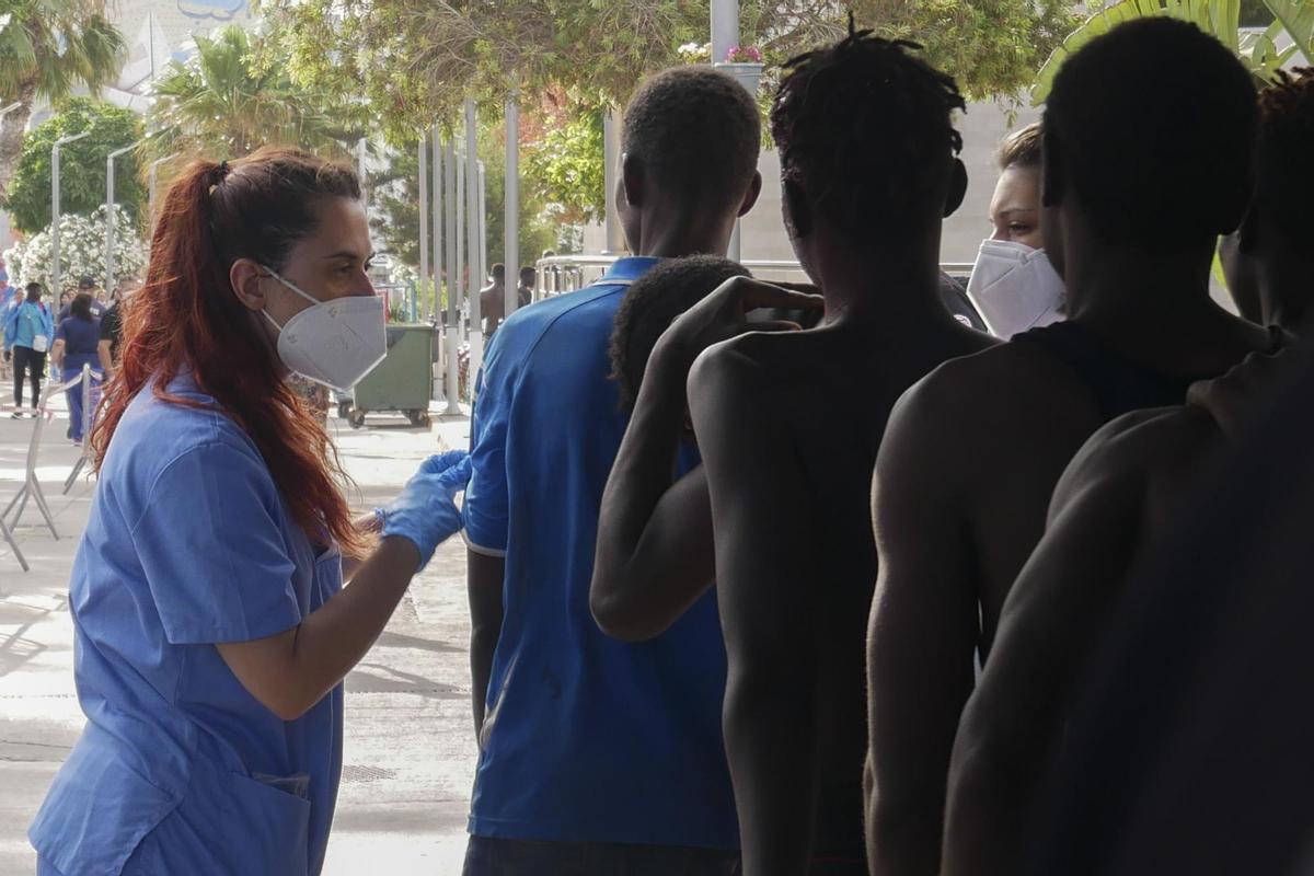 GRAF6935. MELILLA, 24/06/2022.- Dos sanitarias atienden a decenas de inmigrantes han entrado este viernes en Melilla tras romper la puerta de acceso al paso fronterizo de Barrio Chino y saltar por encima de su tejado que separa la ciudad autónoma de Marruecos. EFE/ Paqui Sánchez