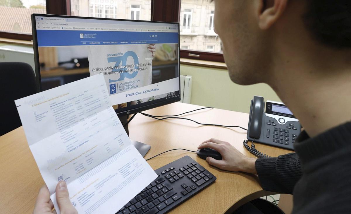 Un joven examina una factura de la electricidad a la vez que consulta la página web del Instituto Galego do Consumo de la Xunta.