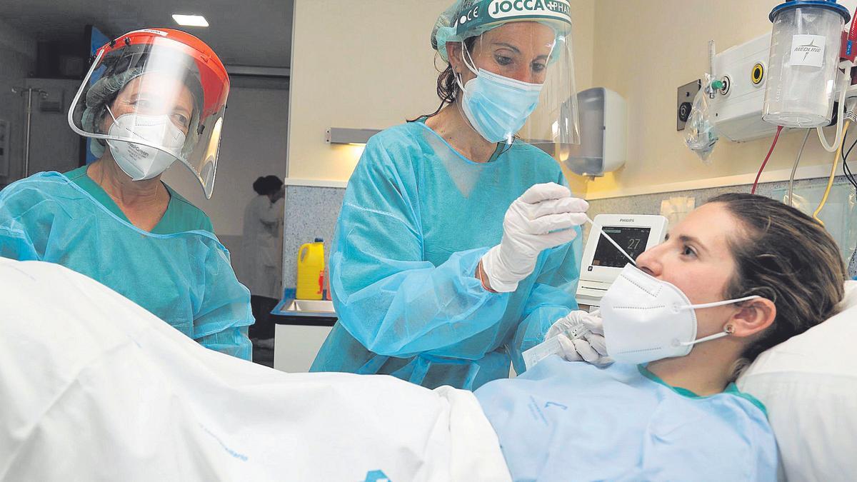 Dos sanitarias realizan una prueba PCR a una mujer ingresada en el Materno Infantil del Santa Lucía de Cartagena.