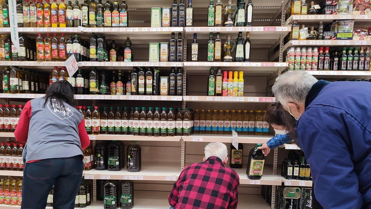 Diverses persones compren oli en un supermercat