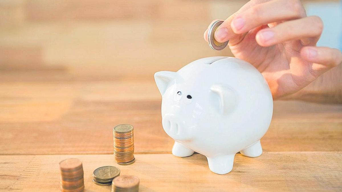 Hand inserting coin in piggy bank