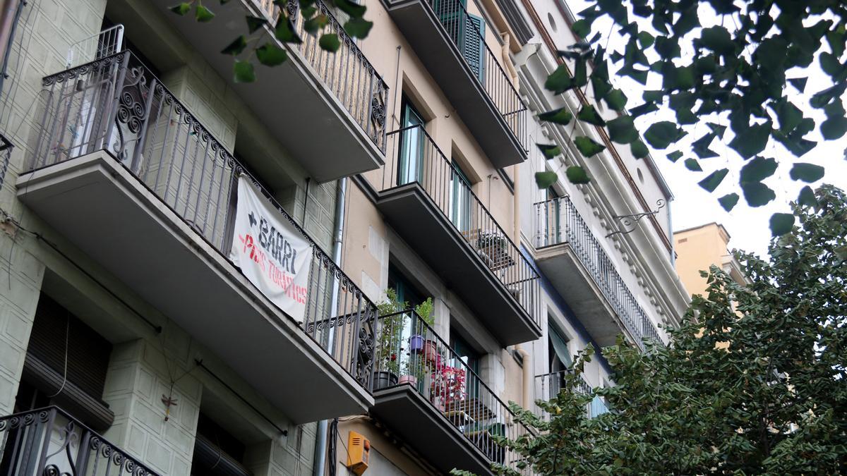 Un cartell amb el lema '+Barri -Pisos Turístics' a la Rambla de Girona. | ACN