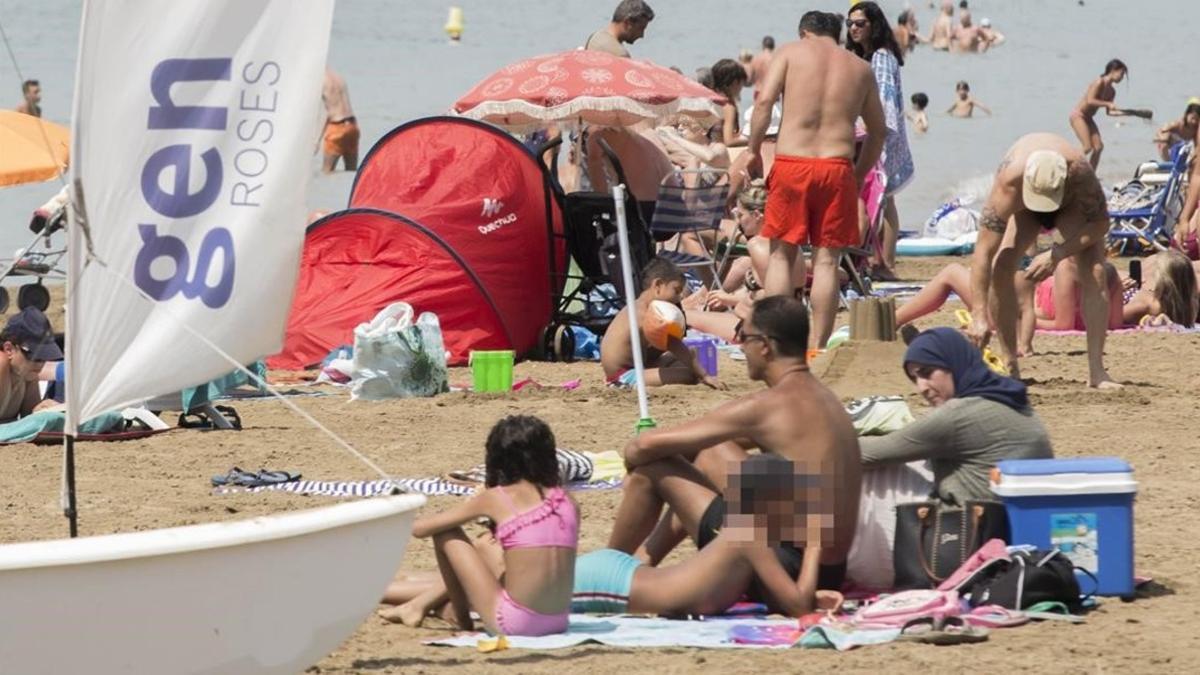 Una mujer en 'burkini', junto a su familia, en la playa de Roses.