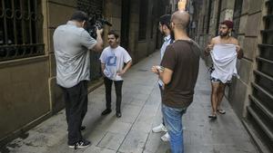 El equipo de ’Quiero ser negro’ graba una escena en Ciutat Vella con Al Sarcoli mirando a cámara y un paseante sorprendido.