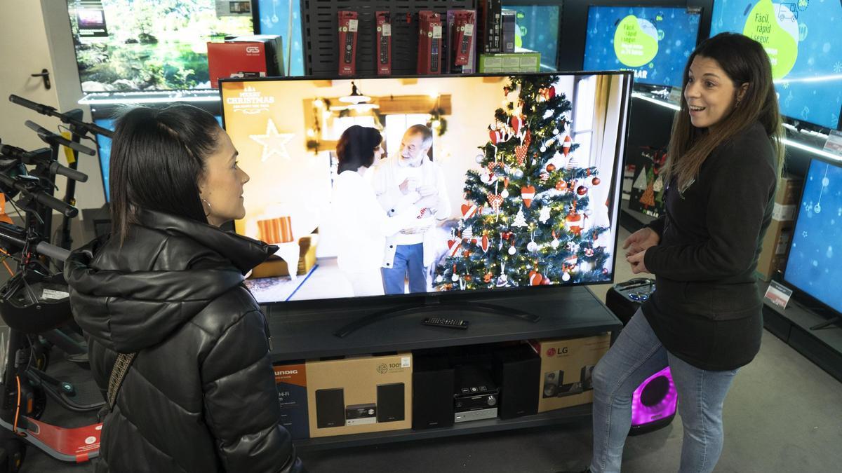Una dependenta de la botiga Milar ensenyant un televisor a una clienta