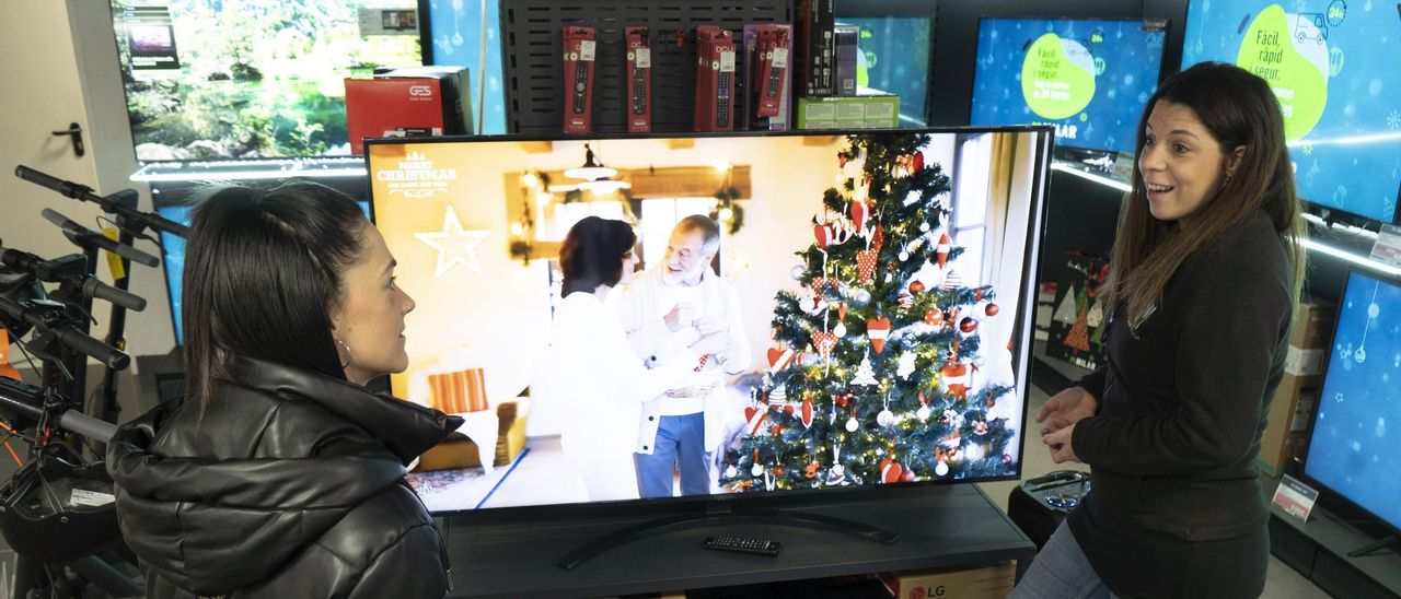 Una dependenta de la botiga Milar ensenyant un televisor a una clienta