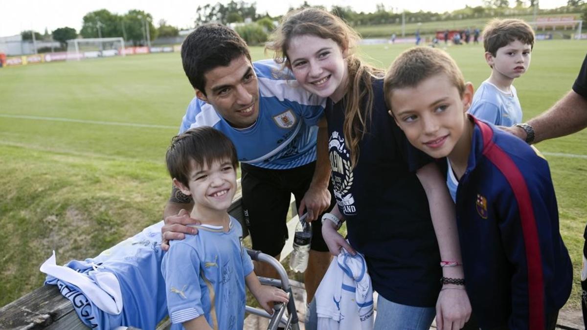 Luis Suárez posa con una jóvenes aficionados tras su primer entrenamiento con la selección uruguaya.