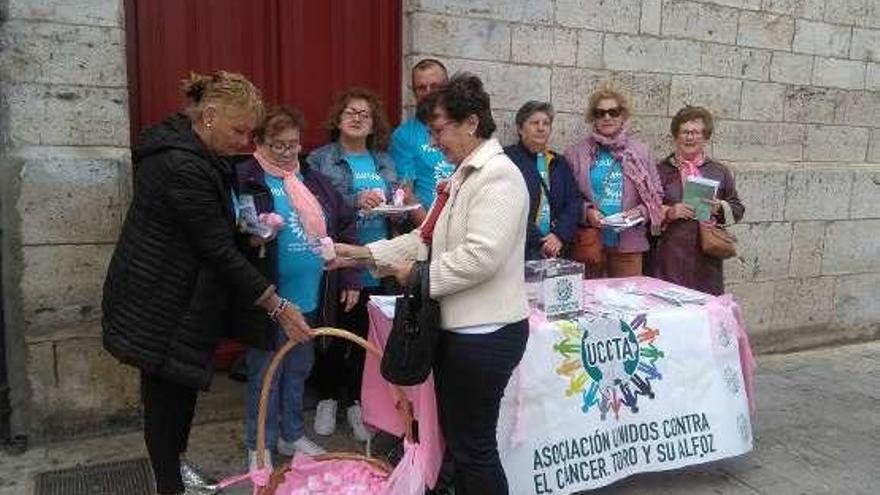 Los voluntarios entregan a una vecina un zapato rosa.