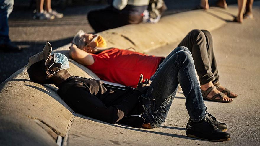 Dos hombres descansan y aprovechan el calor del sol en Santa Cruz .