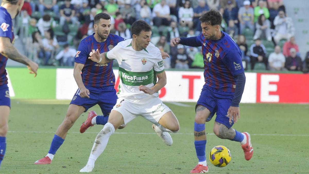 Óscar Plano intenta evitar el marcaje de dos jugadores del Eldense