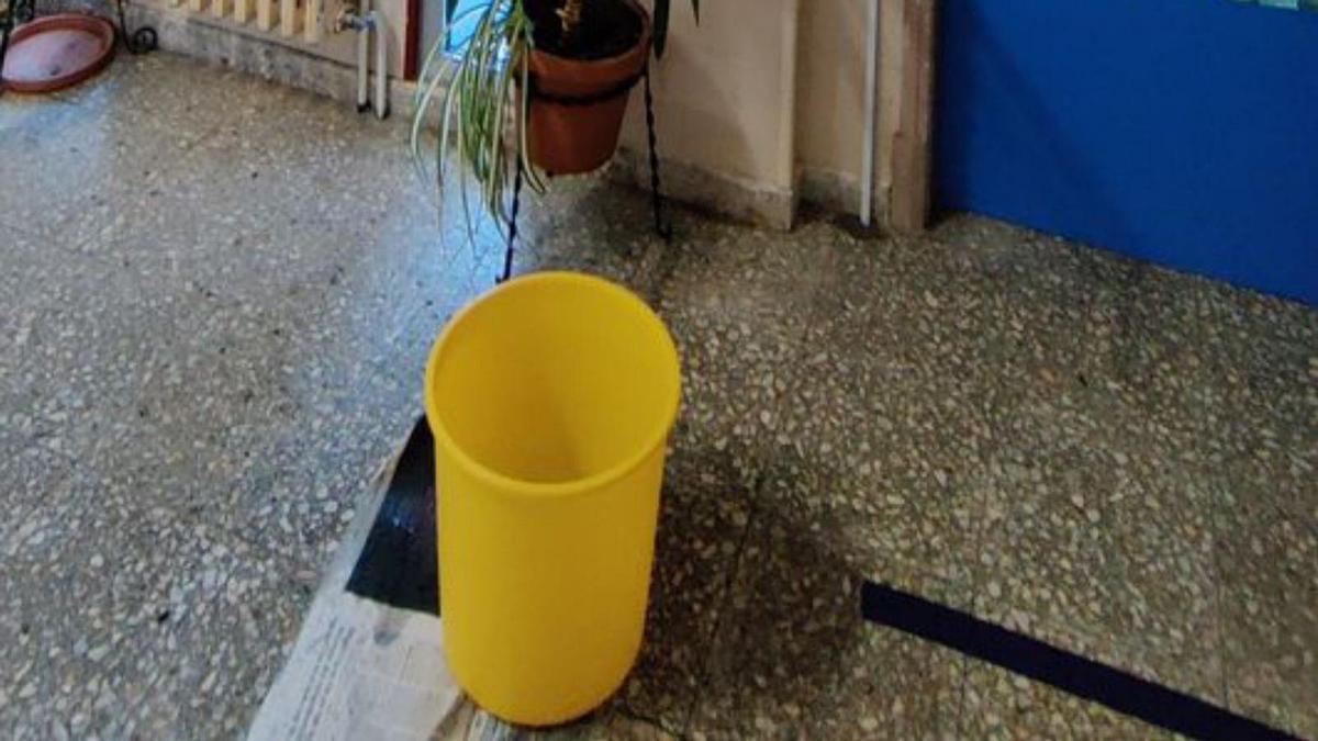 Una papelera, en un pasillo, para recoger el agua de una gotera.